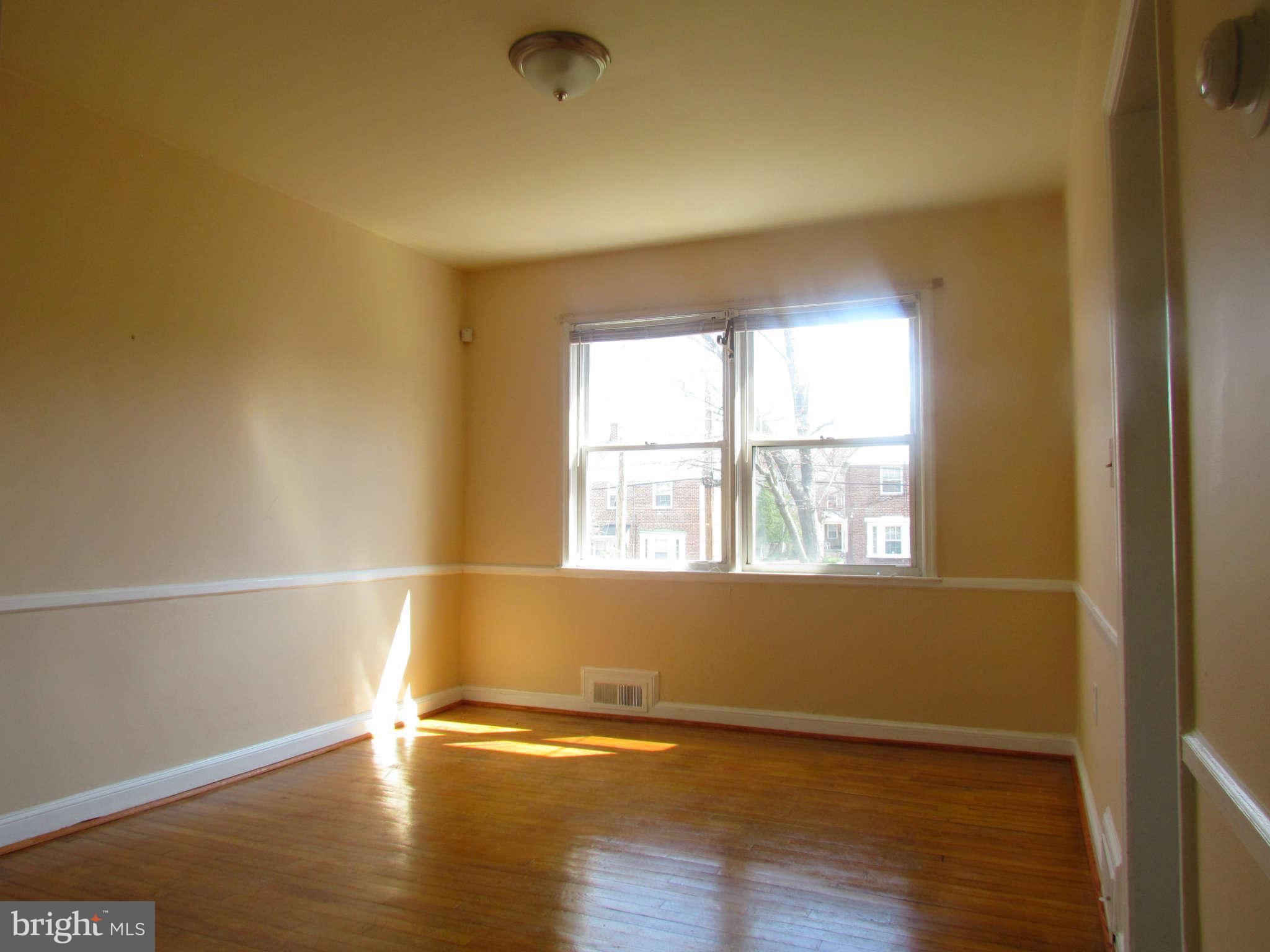 1327 Silverthorne Road Baltimore, MD 21239 - Photo 4 of 16 an empty room with wooden floor and windows
