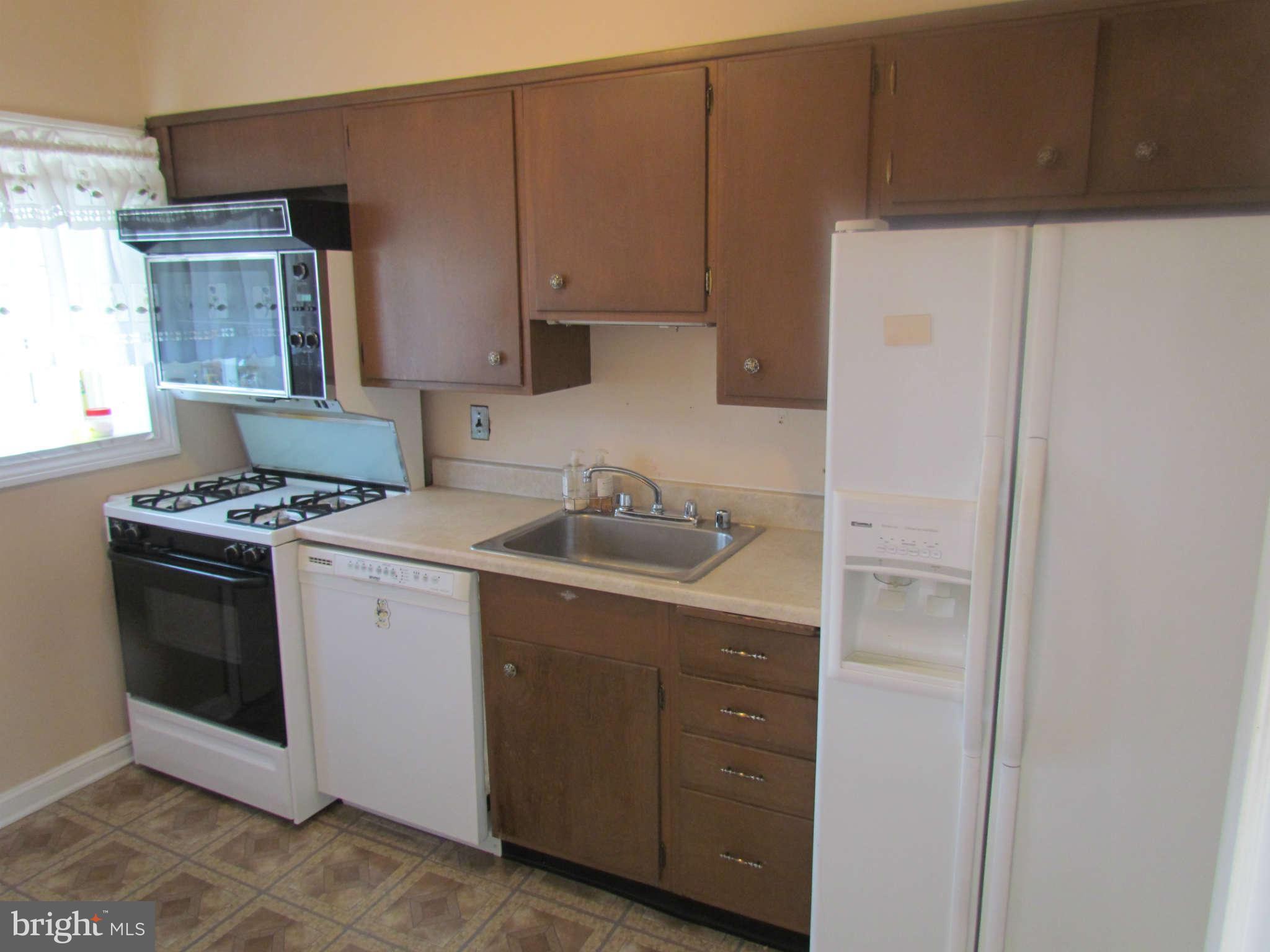 1327 Silverthorne Road Baltimore, MD 21239 - Photo 6 of 16 a kitchen with a sink a stove and a refrigerator
