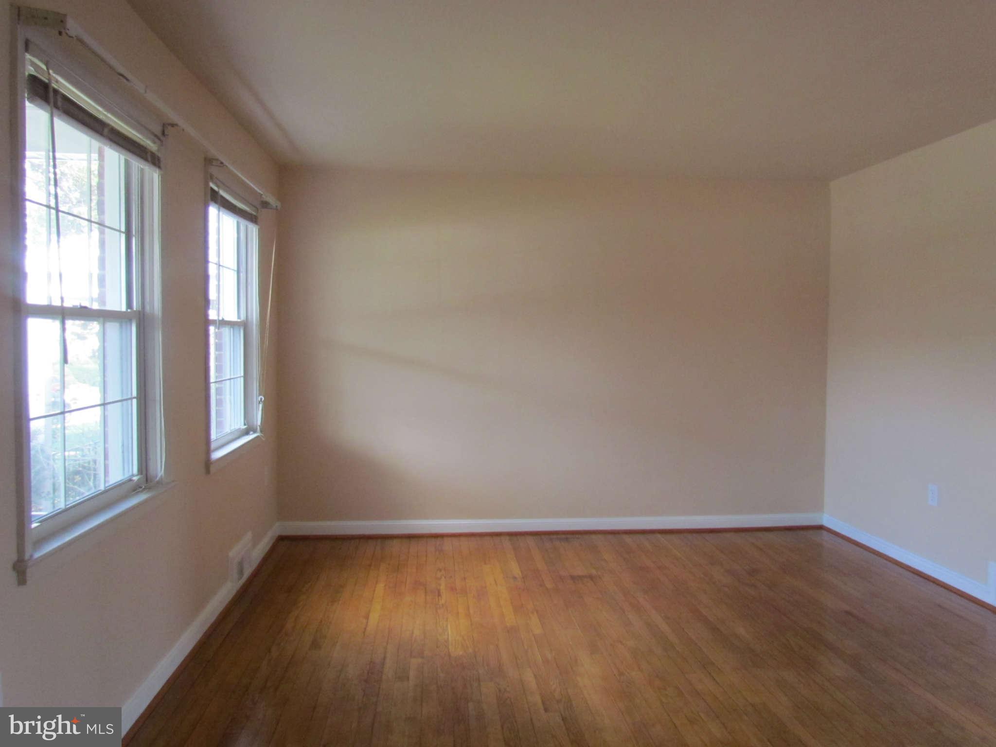 1327 Silverthorne Road Baltimore, MD 21239 - Photo 7 of 16 an empty room with wooden floor and windows