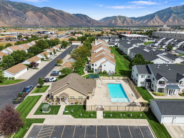 482 South 2500th West, Unit 2 Springville, UT 84663 - Photo 39 of 52 Community pool area with surrounding fencing, adjacent multi-story residences, and distant mountainous terrain
