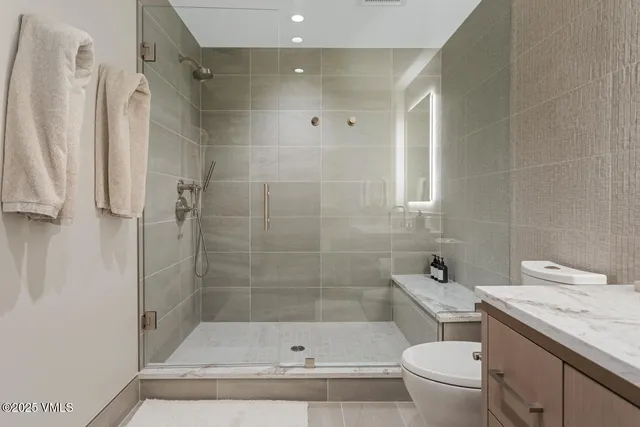 a bathroom with a granite countertop bathtub shower sink vanity and toilet