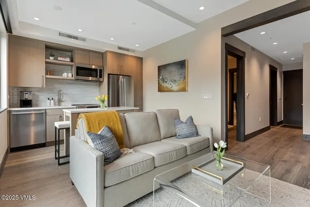 a living room with stainless steel appliances furniture and kitchen view