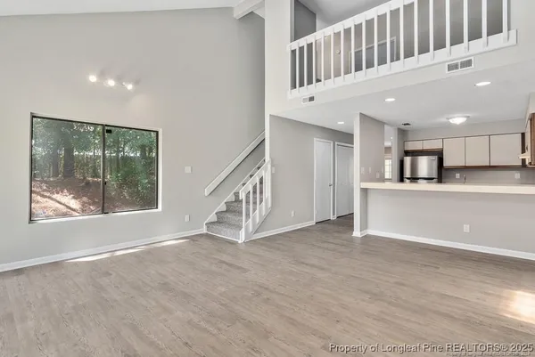 a view of an empty room with a window and kitchen view