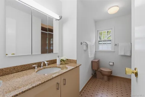 a bathroom with a granite countertop sink a toilet and a mirror