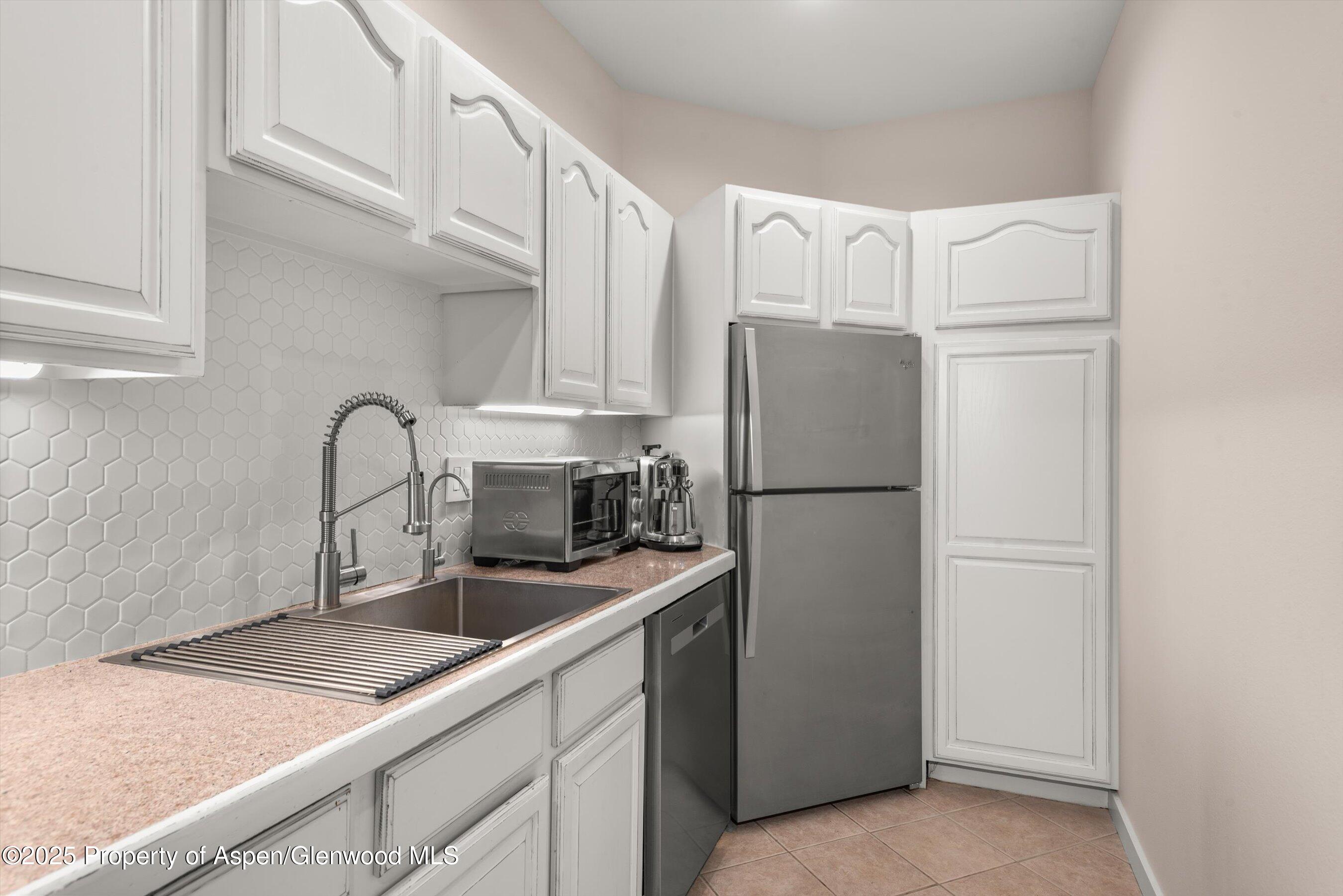 1400 East Valley Road, Unit 115 Basalt, CO 81621 - Photo 10 of 17 a kitchen with stainless steel appliances granite countertop a refrigerator sink and white cabinets