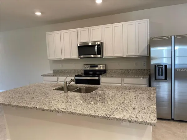 a kitchen with stainless steel appliances granite countertop a stove a sink and a microwave