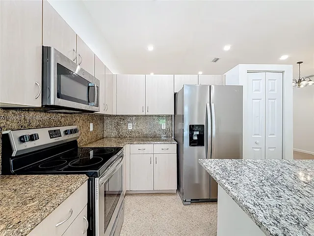 a kitchen with stainless steel appliances granite countertop a sink stove microwave and refrigerator