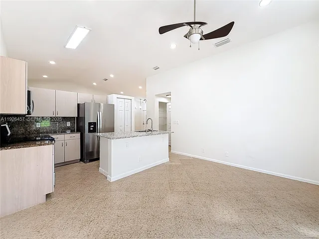 a large kitchen with a refrigerator and white cabinets
