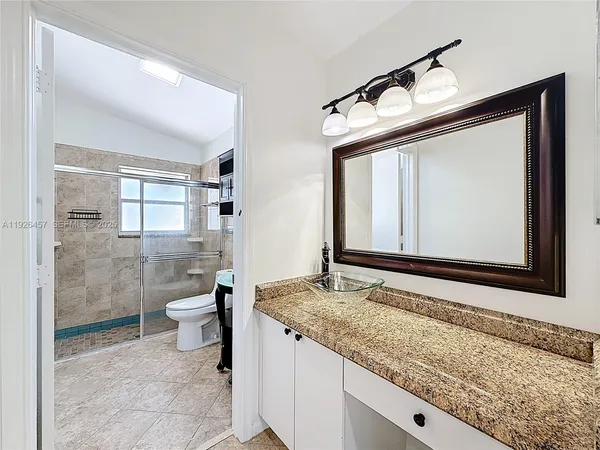 a bathroom with a granite countertop sink toilet and shower