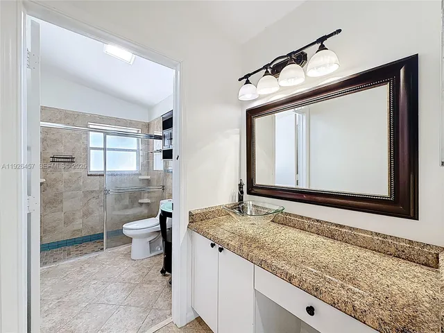 a bathroom with a granite countertop sink toilet and shower