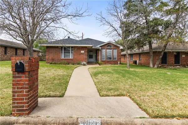 a front view of a house with a yard and trees
