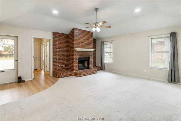 an empty room with wooden floor fireplace and windows