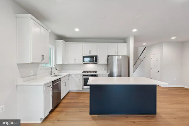 a large kitchen with stainless steel appliances kitchen island granite countertop a stove top oven a refrigerator a sink and dishwasher with wooden floor