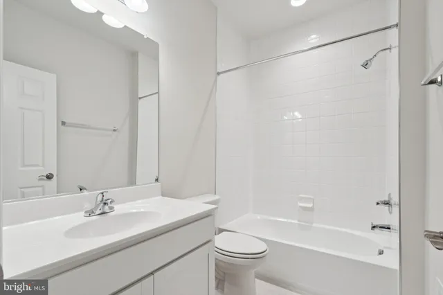 a bathroom with a bathtub shower sink vanity mirror and toilet