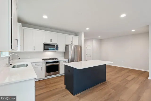 a large kitchen with stainless steel appliances a white stove top oven and white cabinets