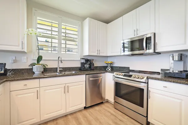 a kitchen with granite countertop white cabinets and white appliances