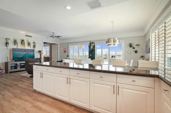 a kitchen with stainless steel appliances kitchen island granite countertop a stove a refrigerator a white table and chairs with wooden floor