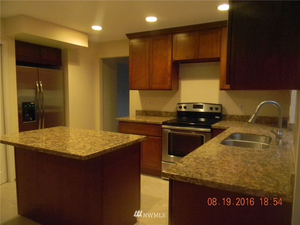 11224 Southeast 188th Place Renton, WA 98055 - Photo 16 of 16 a kitchen with kitchen island granite countertop a sink a counter top space and cabinets