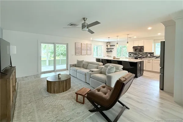 a living room with furniture kitchen view and a large window