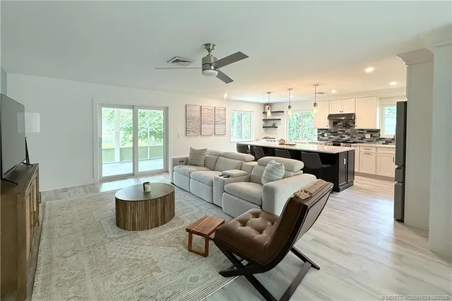 a living room with furniture kitchen view and a large window