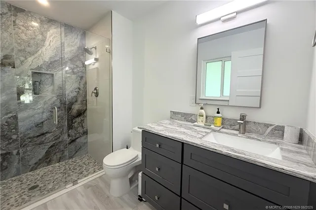 a bathroom with a granite countertop sink toilet a mirror and shower