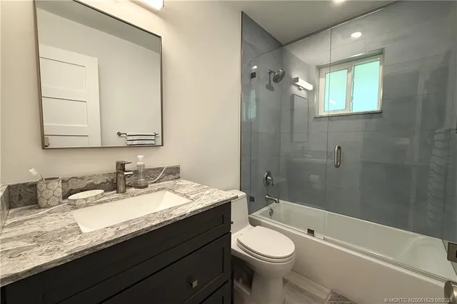 a bathroom with a granite countertop sink toilet and shower