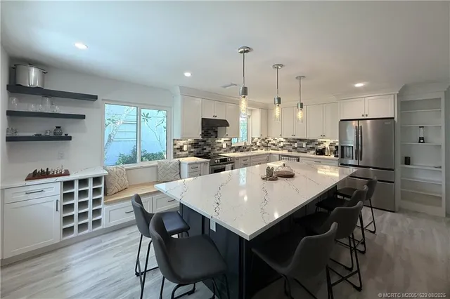 a kitchen with stainless steel appliances a dining table chairs stove refrigerator and cabinets