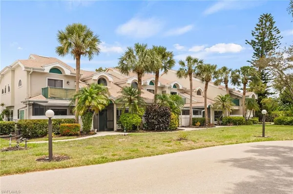 a front view of a house with a yard and palm trees
