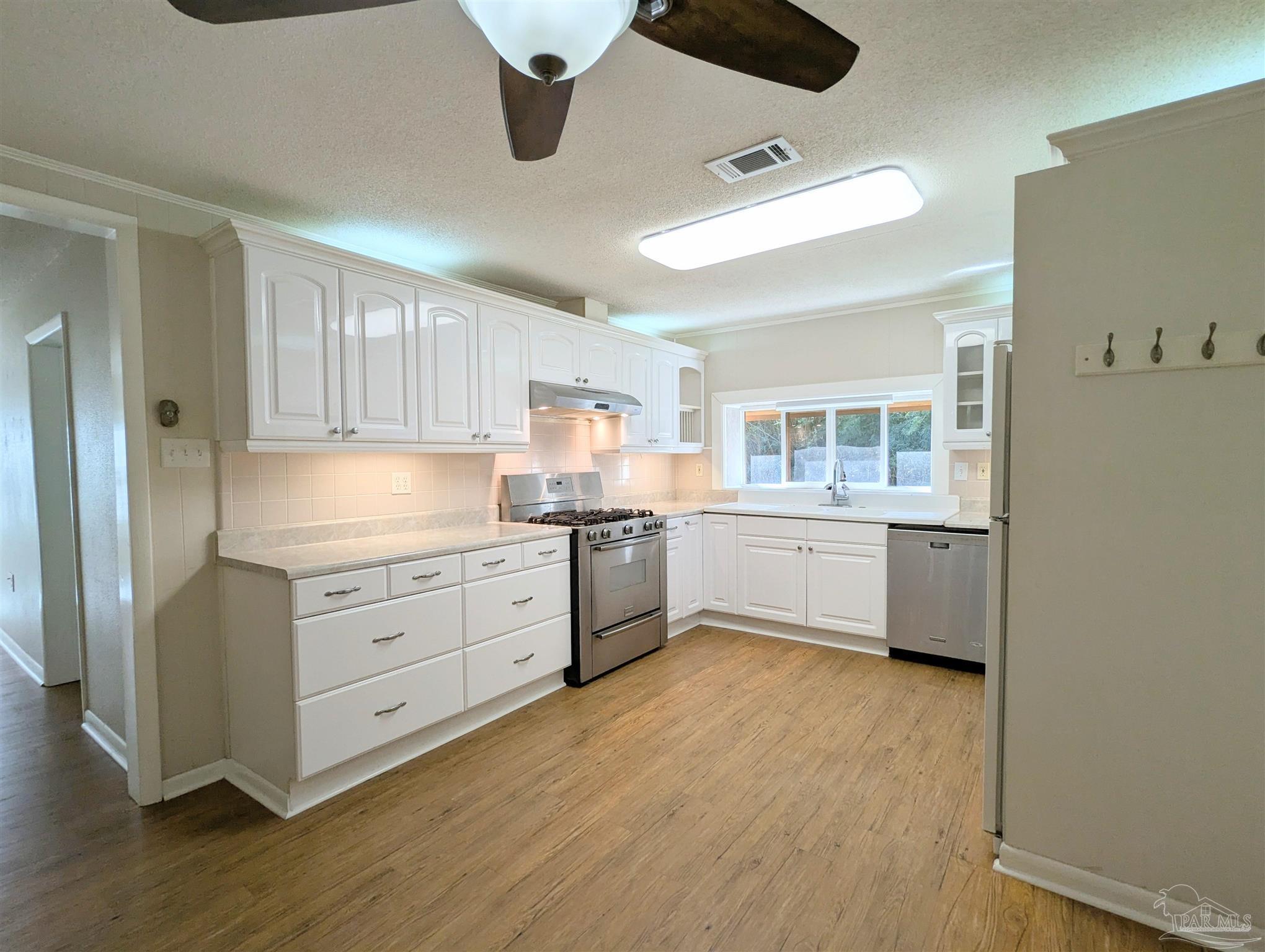 4301 Willow Street Pace, FL 32571 - Photo 11 of 25 a kitchen with stainless steel appliances white cabinets and wooden floors