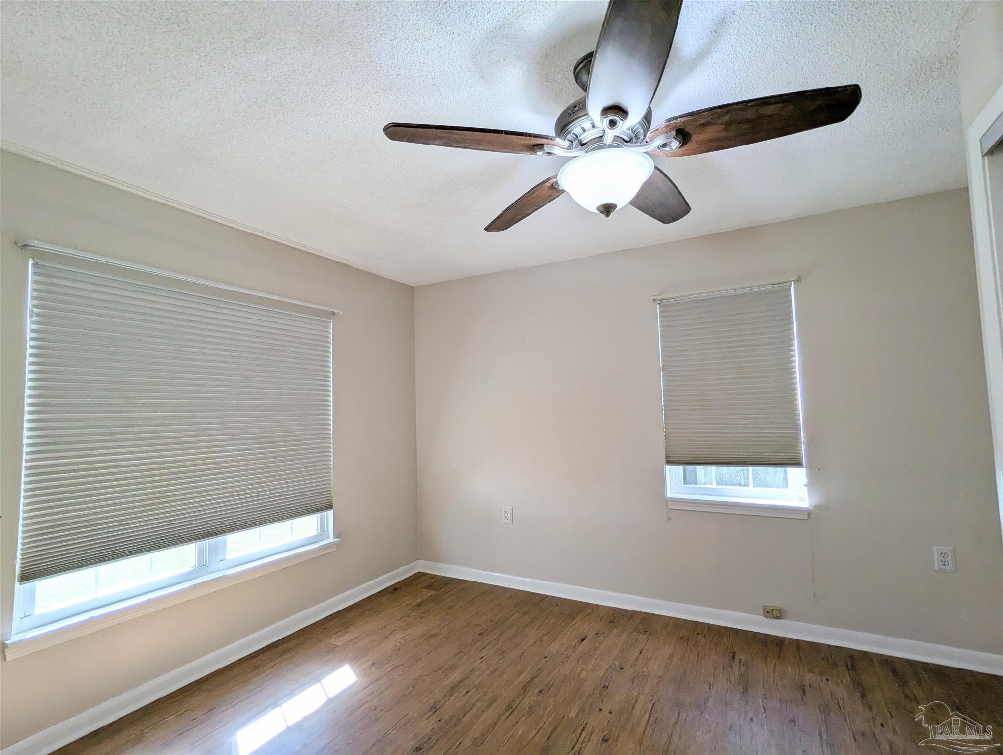 4301 Willow Street Pace, FL 32571 - Photo 8 of 25 an empty room with wooden floor fan and windows