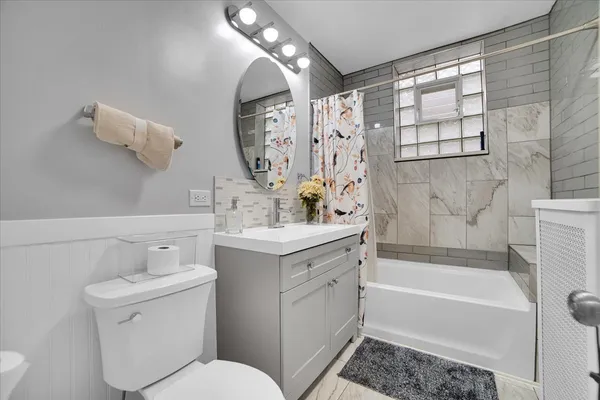 a bathroom with a toilet a sink a mirror a bathtub and shower