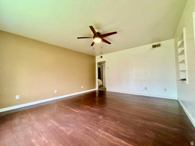 704 North 200 East Logan, UT 84321 - Photo 3 of 24 Empty room with a ceiling fan, dark wood-style floors, and built in features