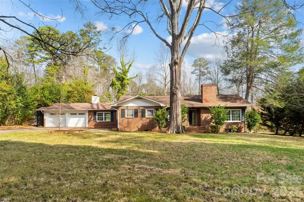 a view of a house with a big yard and large trees
