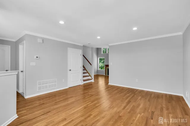 a view of an empty room with wooden floor and closet