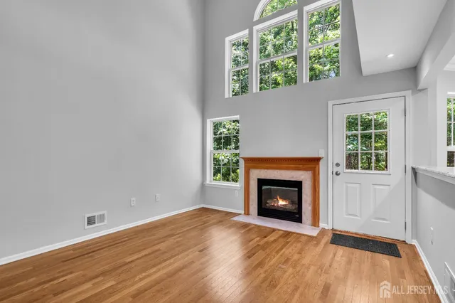 an empty room with wooden floor fireplace and windows
