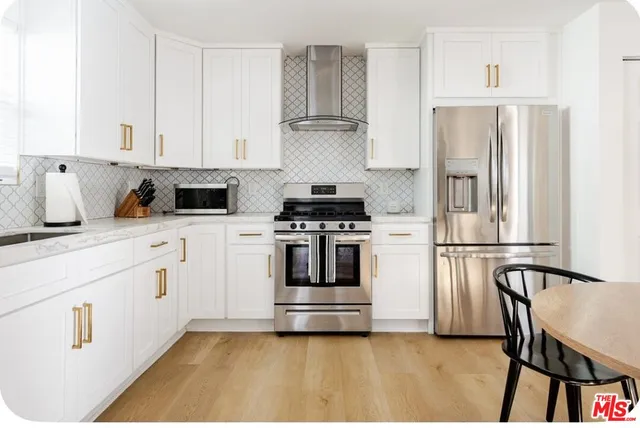 a kitchen with cabinets stainless steel appliances and wooden floor