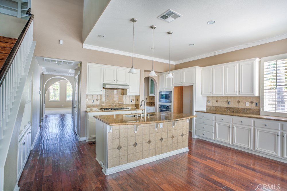 3782 Carson Way Yorba Linda, CA 92886 - Photo 14 of 48 a kitchen with stainless steel appliances kitchen island granite countertop wooden floors and white cabinets