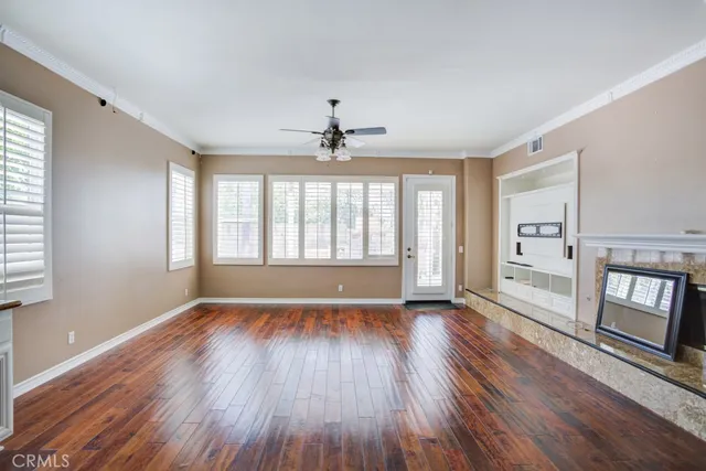 a view of a living room with wooden floor and a ceiling fan
