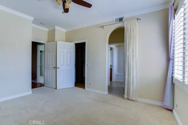 an empty room with chandelier fan and windows
