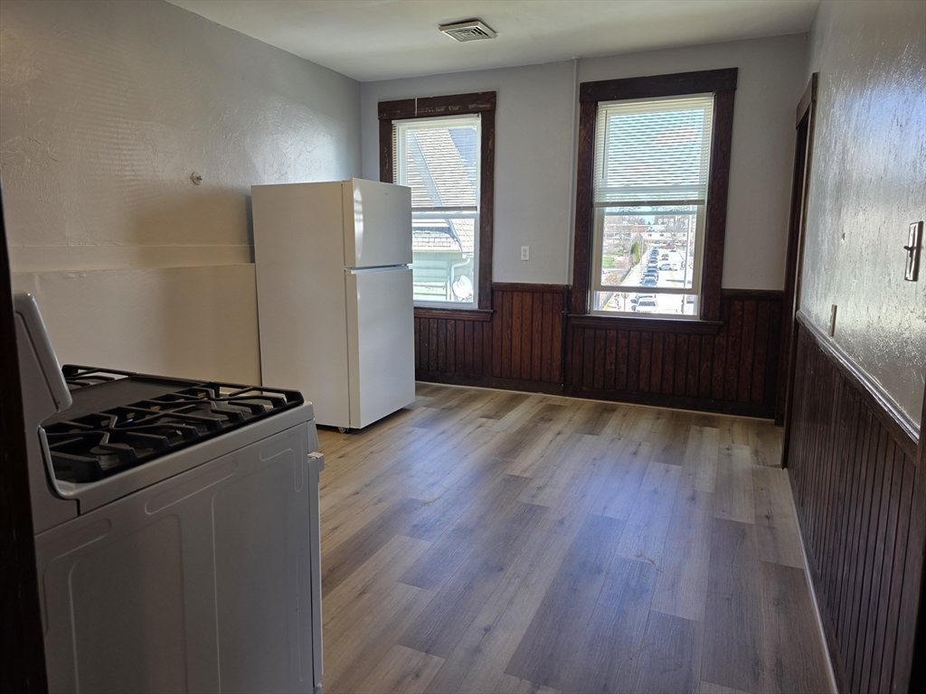 2 Hillside Street, Unit 3 Worcester, MA 01610 - Photo 7 of 23 an empty room with wooden floor a cabinet and windows