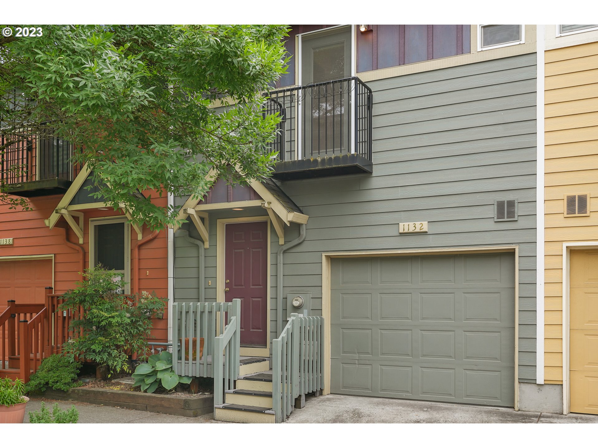 a side view of a house with a yard and potted plants
