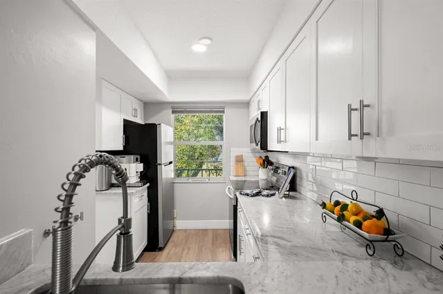 a kitchen with stainless steel appliances granite countertop a sink refrigerator and window