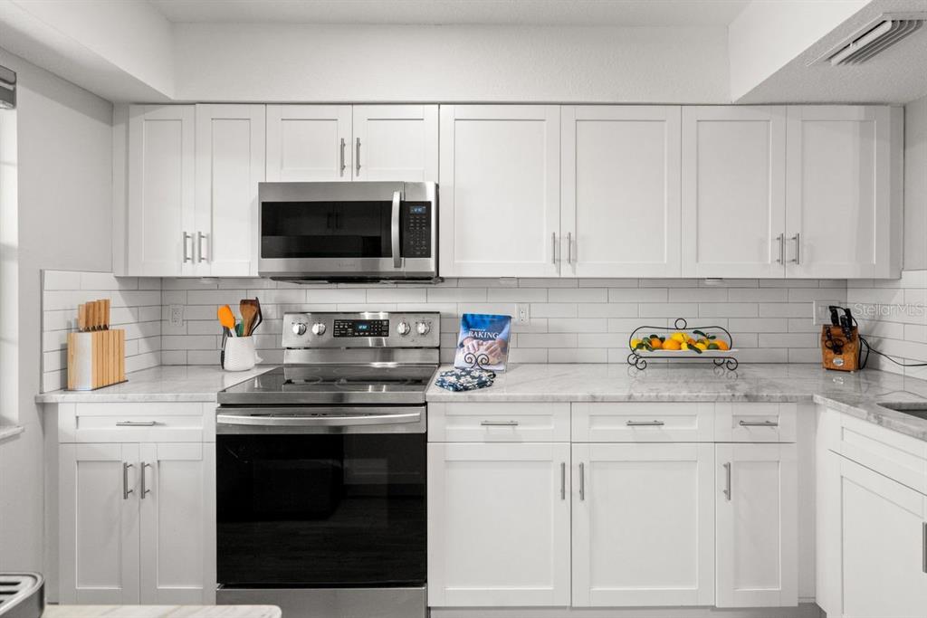 300 Clyde Lane, Unit 215 Dunedin, FL 34698 - Photo 12 of 60 a kitchen with white cabinets stainless steel appliances and sink