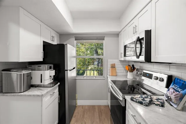 a kitchen with stainless steel appliances a stove a sink dishwasher a refrigerator and a stove with wooden floor