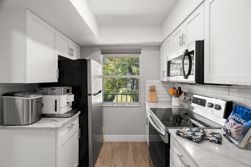 300 Clyde Lane, Unit 215 Dunedin, FL 34698 - Photo 14 of 60 a kitchen with stainless steel appliances a stove a sink dishwasher a refrigerator and a stove with wooden floor