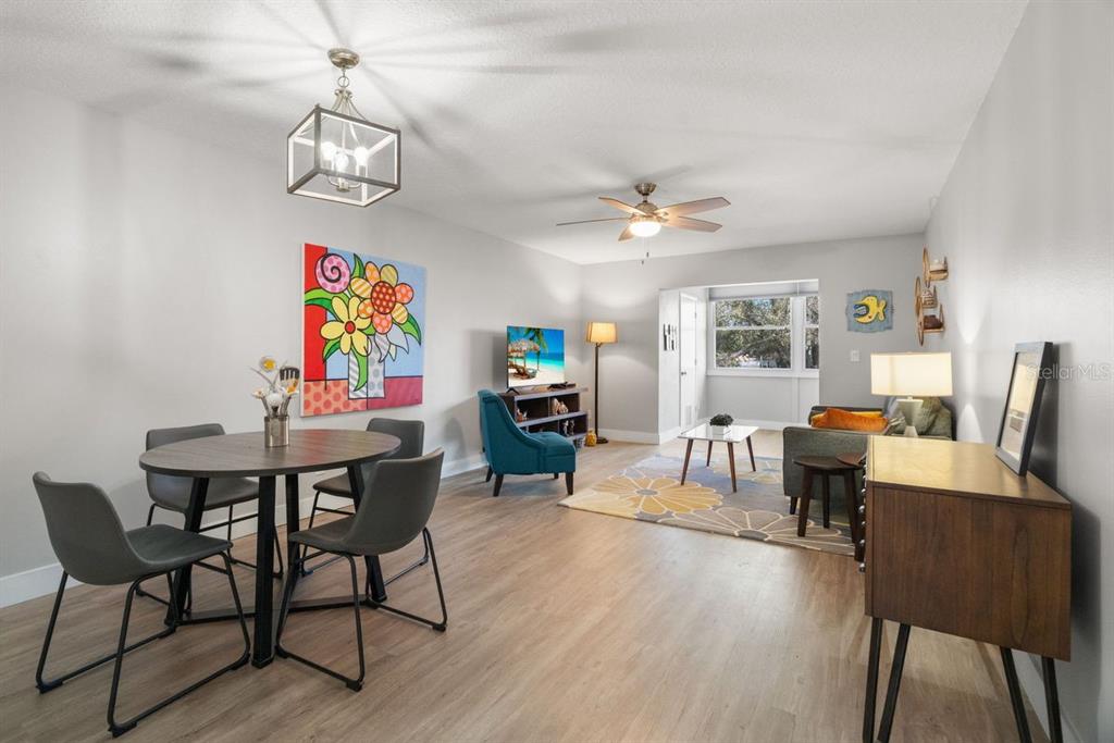 300 Clyde Lane, Unit 215 Dunedin, FL 34698 - Photo 7 of 60 a view of a dining room with furniture a chandelier and wooden floor