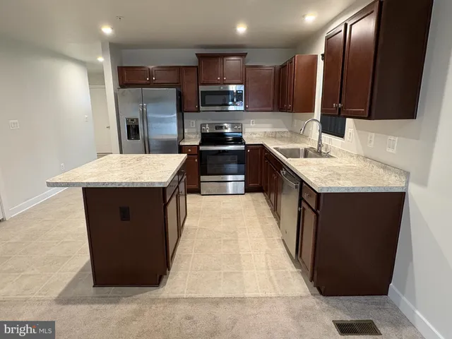 a kitchen with stainless steel appliances kitchen island granite countertop a stove a sink and a refrigerator
