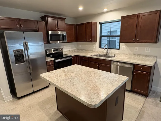 a kitchen with stainless steel appliances granite countertop a sink stove microwave and refrigerator