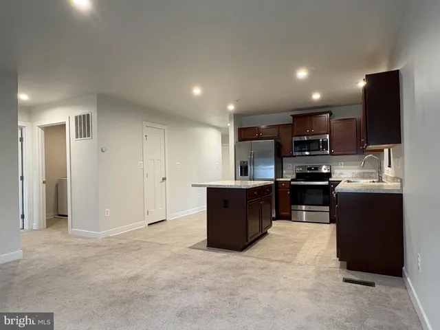 a kitchen with stainless steel appliances granite countertop a refrigerator and a stove top oven