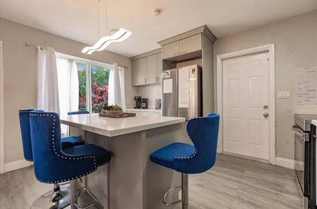 a kitchen with stainless steel appliances granite countertop a sink a stove a refrigerator and a dining table with wooden floor